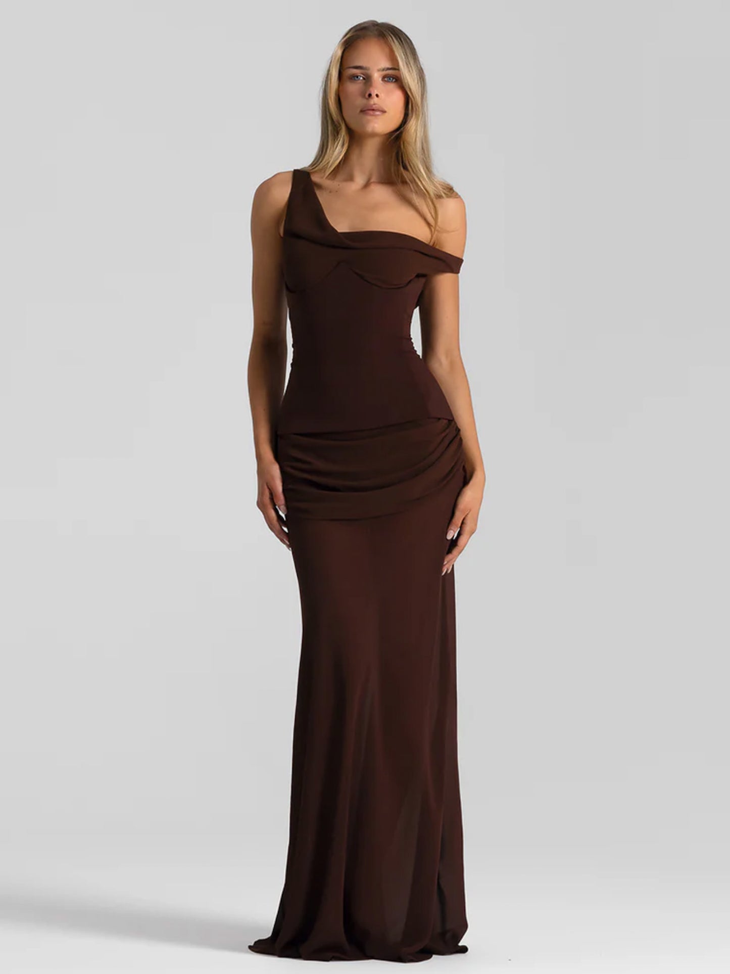 Woman wearing a brown one-shoulder evening gown on a gray background