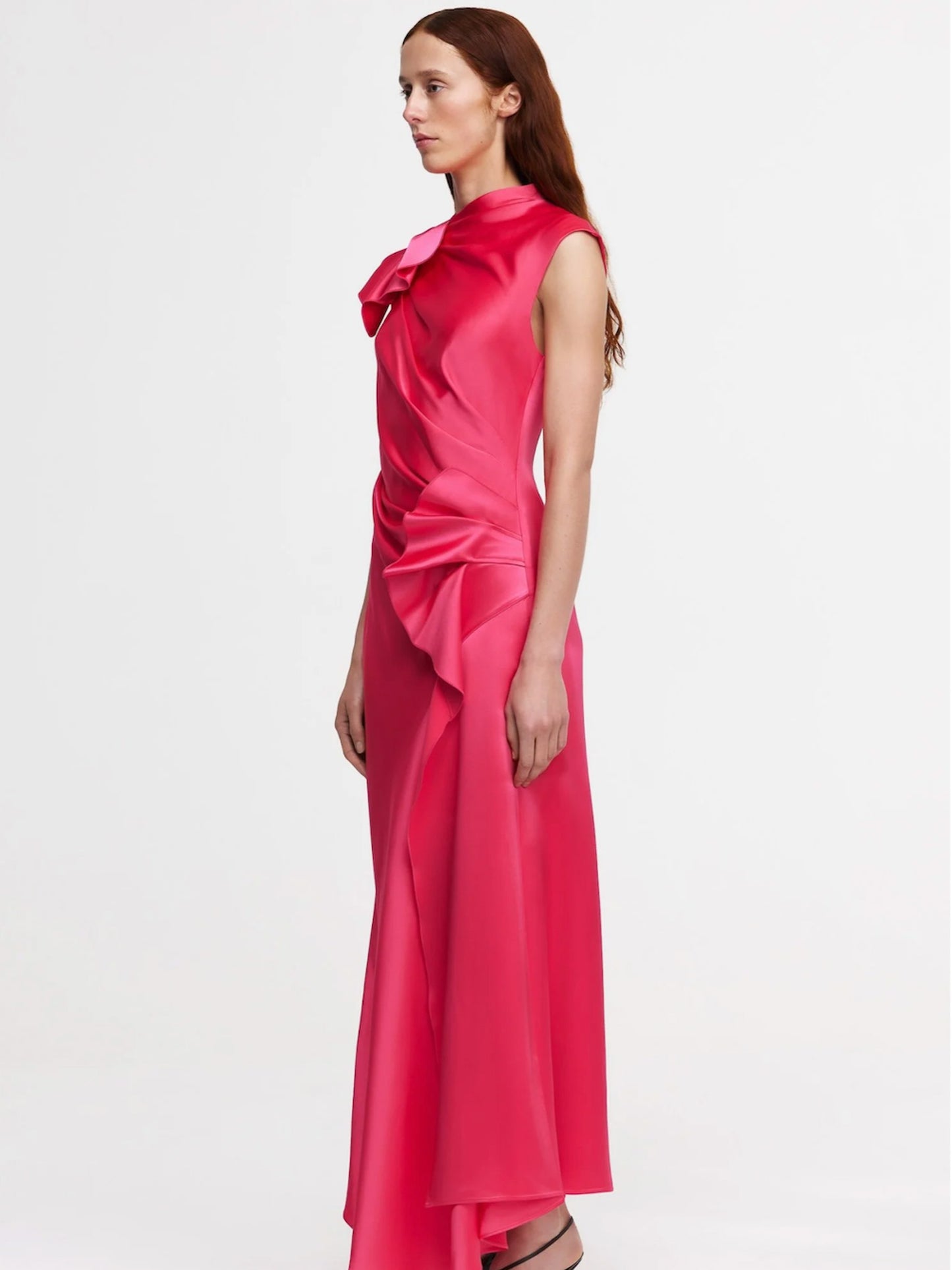 Woman wearing a pink satin dress with a bow detail on a white background