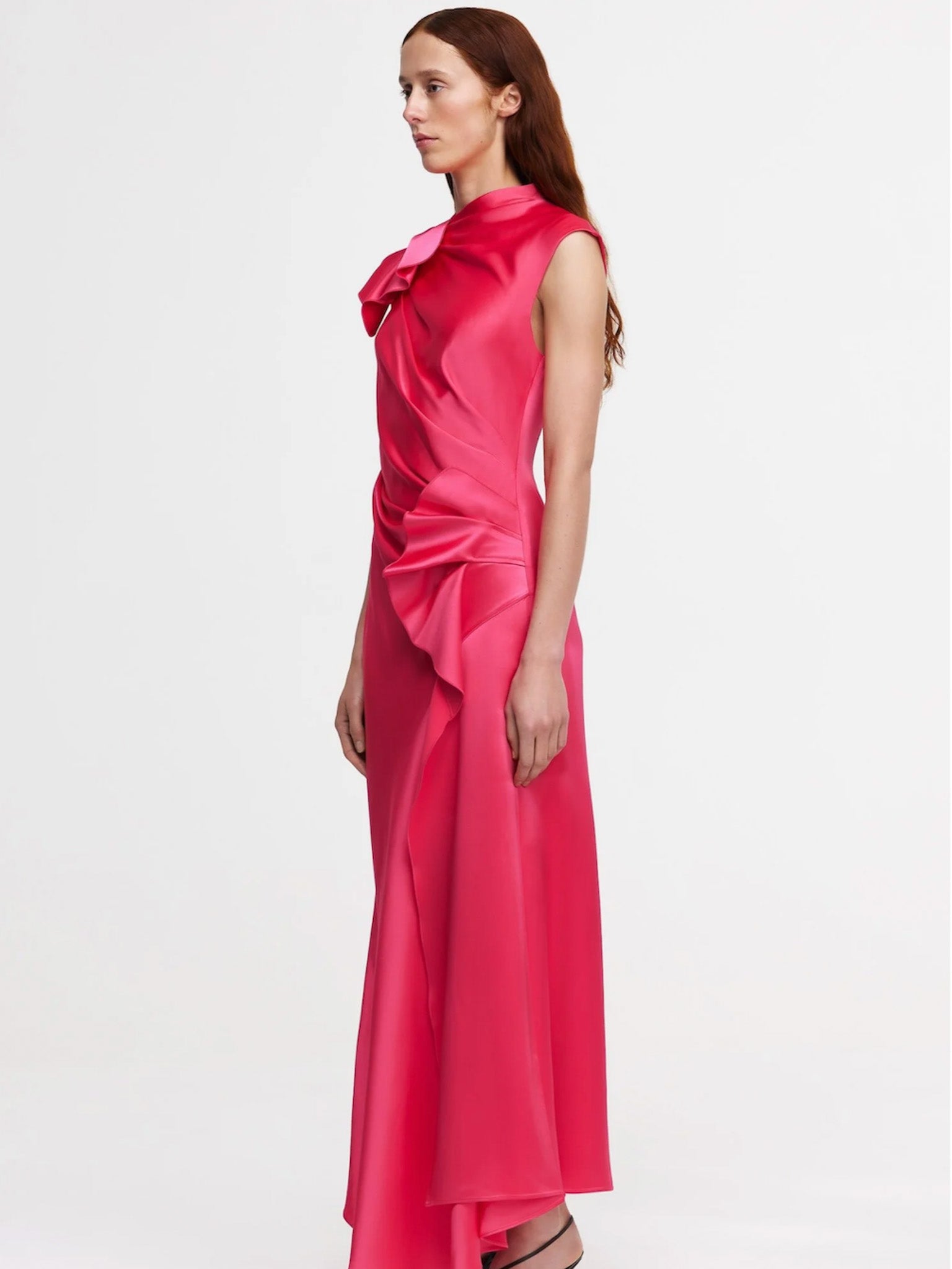 Woman wearing a pink satin dress with a bow detail on a white background